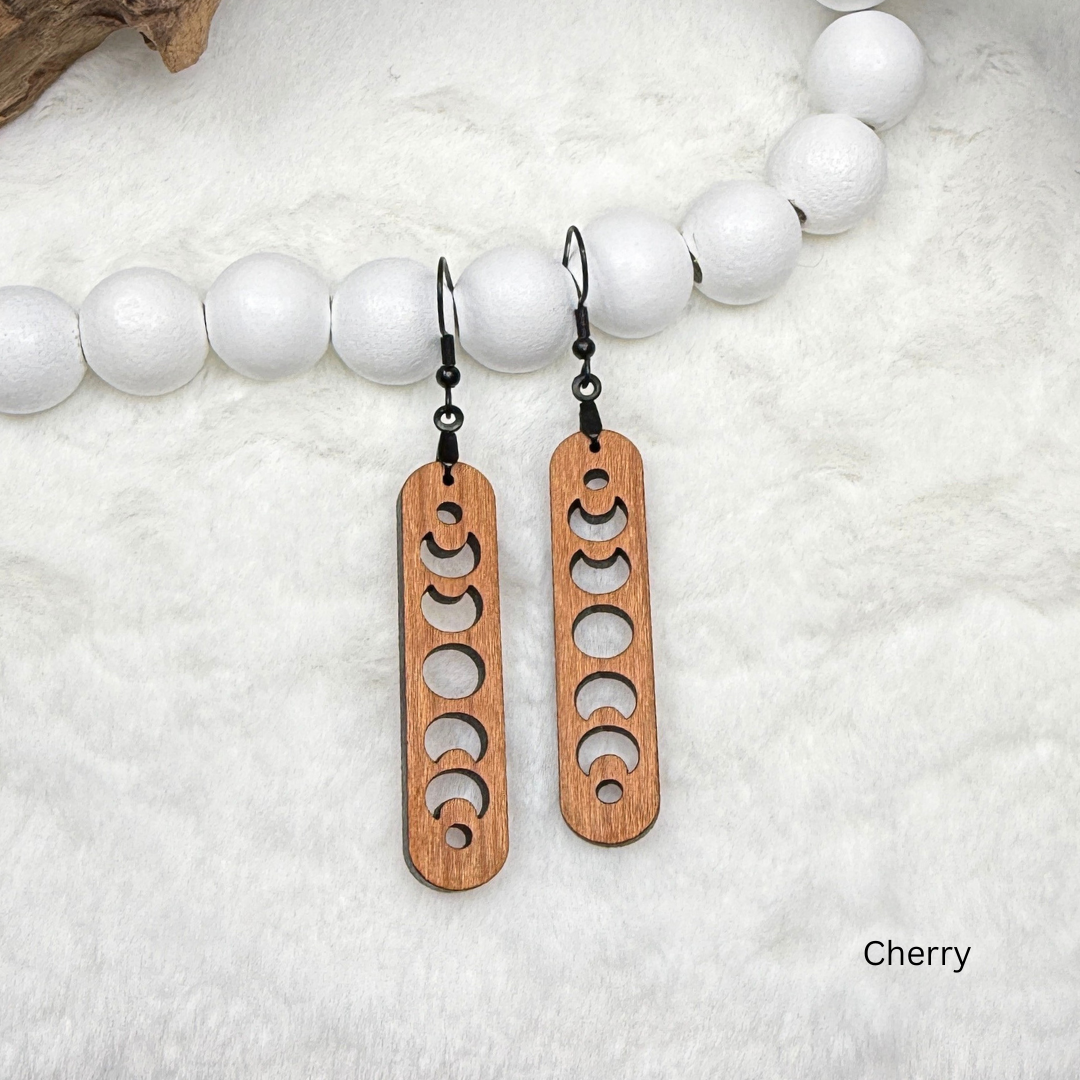 Cherry wood earrings with laser cut crescent moon. Dangle earrings with black stainless steel hooks and silicone backers. Finished with natural wood oil.