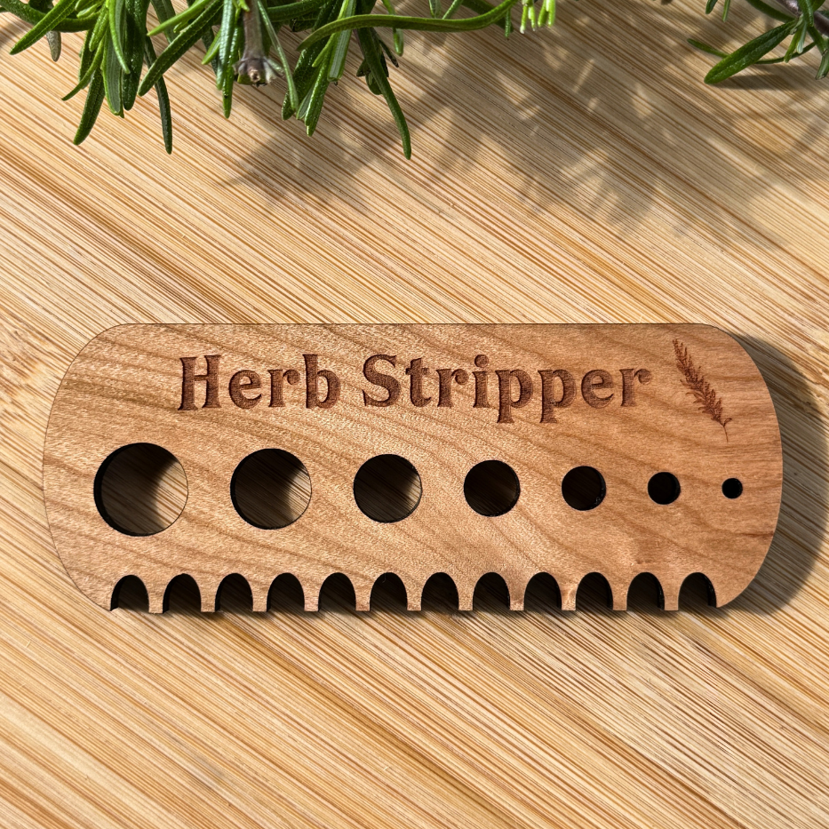 Wooden herb stripper with 'Herb Stripper' engraving on a wooden surface with herbs.