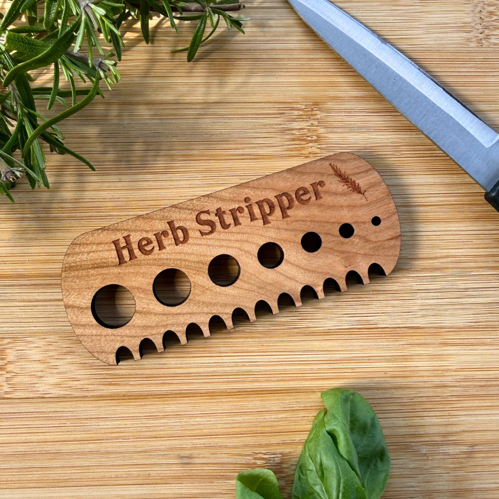 Wooden herb stripper on a wooden cutting board with herbs and a knife.