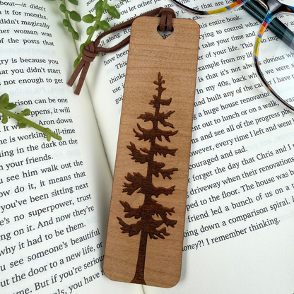 Wooden bookmark with tree design on a book page, cherry wood and brown faux suede rope.