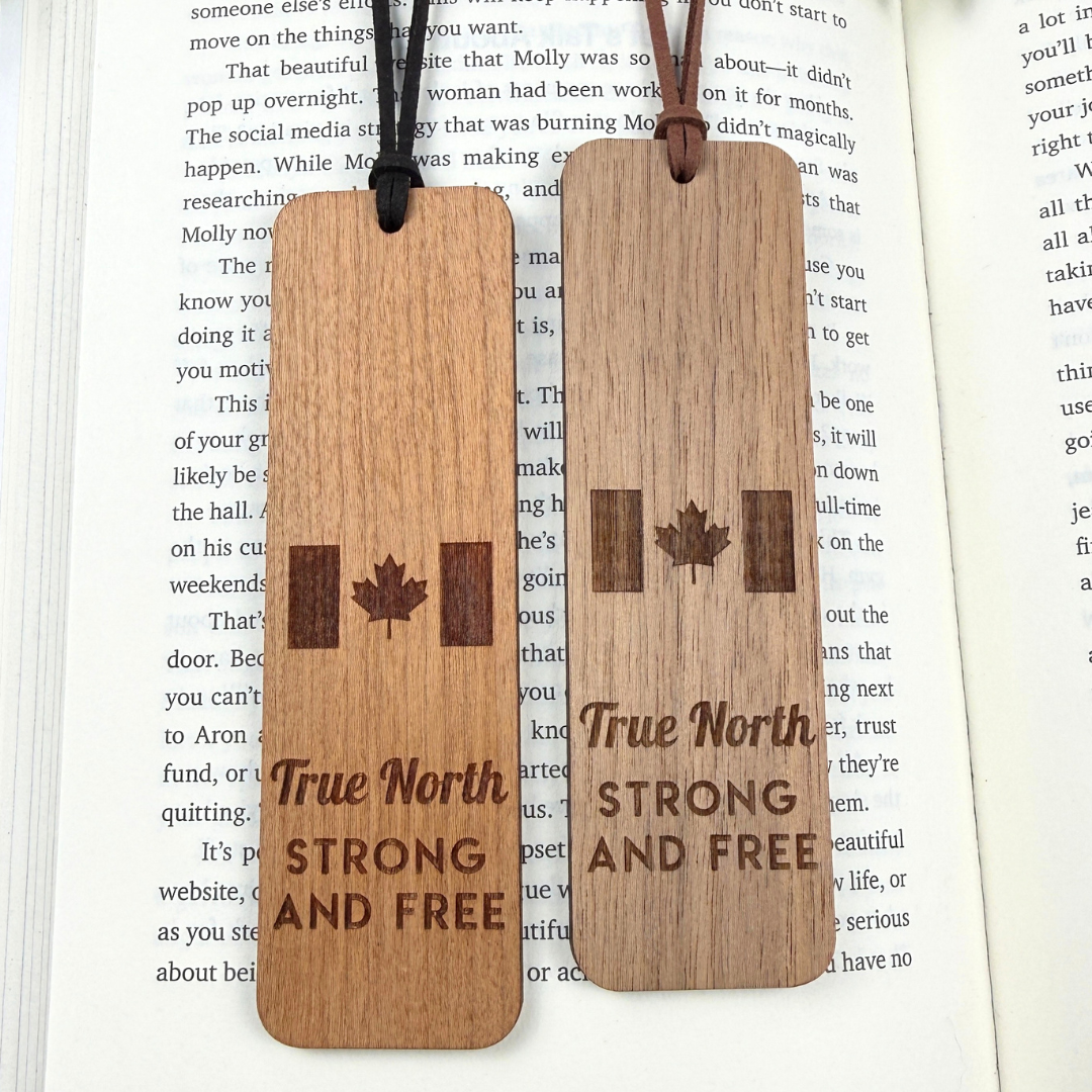 Two wooden bookmarks with 'True North Strong and Free' text and a maple leaf on an open book.