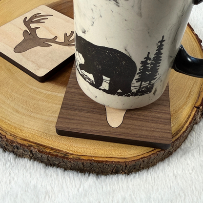 Bear-patterned mug resting on a walnut deer inlay coaster on a wood slice.