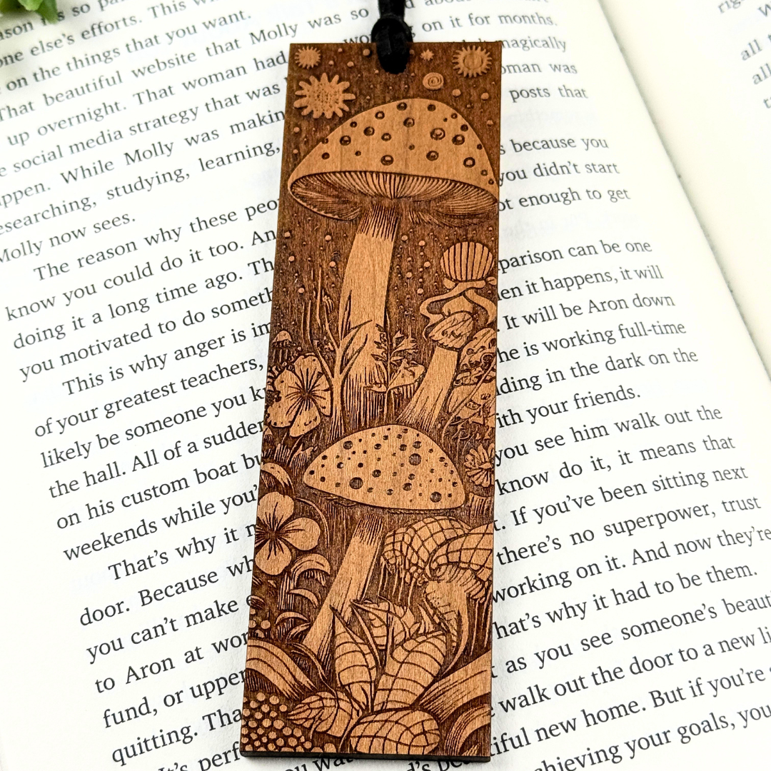Wooden bookmark engraved with a mushroom design on a book page. Cherry wood.
