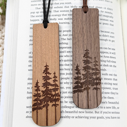 Two wooden bookmarks with tree engravings on an open book. Cherry and walnut wood.