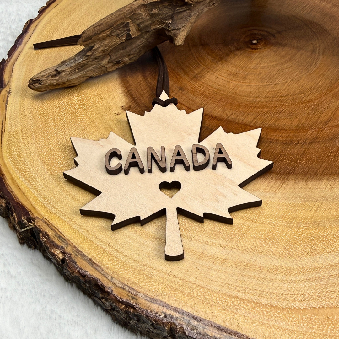 Canadian maple leaf ornament made from maple and walnut wood displayed on a rustic wood background.