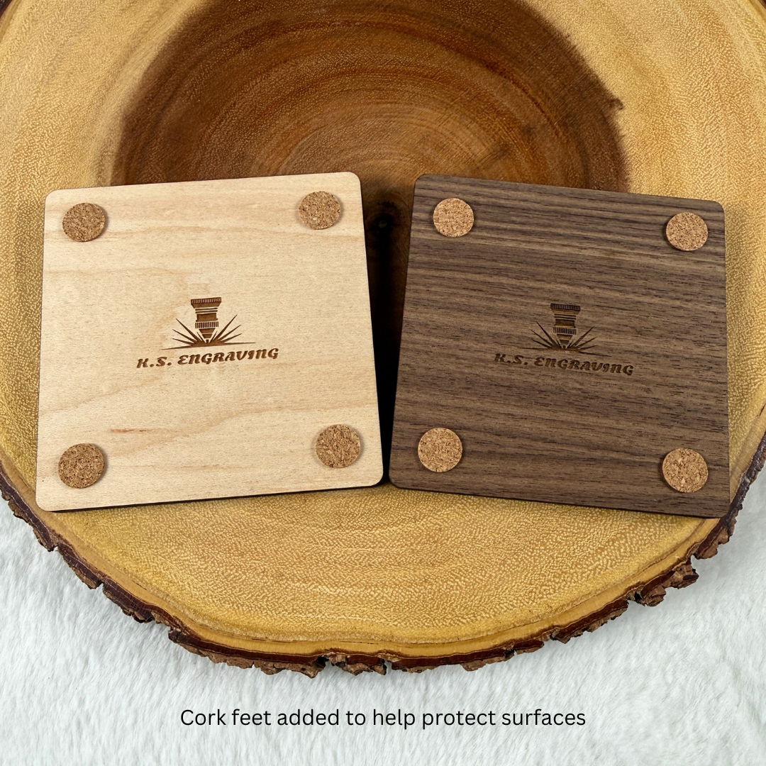 Backs of maple and walnut wood coasters showing protective cork feet and engraved maker details.