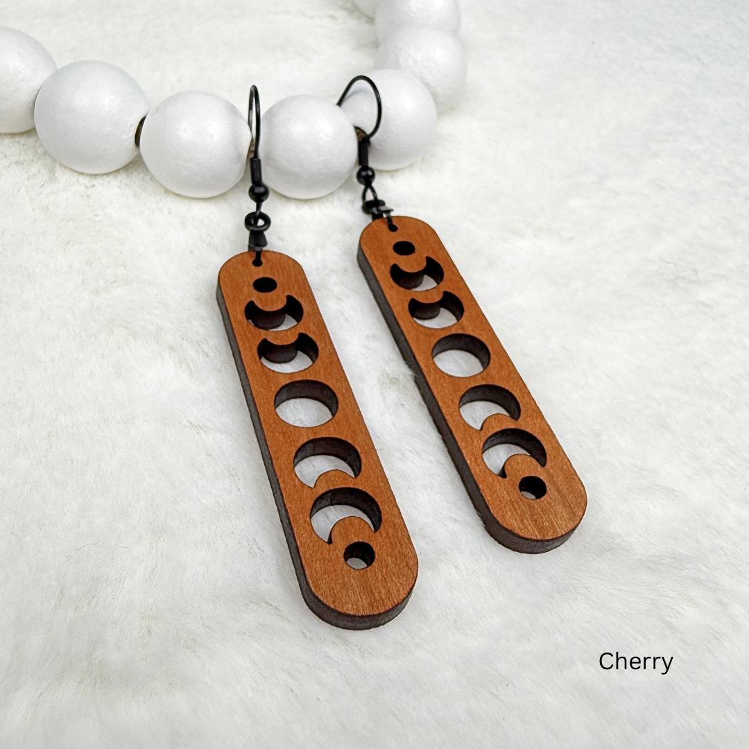 Cherry wood earrings with laser cut crescent moon. Dangle earrings with black stainless steel hooks and silicone backers. Finished with natural wood oil.