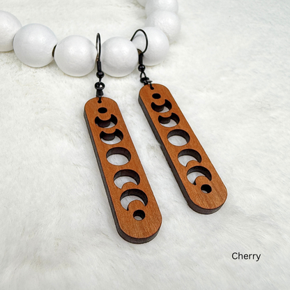 Cherry wood earrings with laser cut crescent moon. Dangle earrings with black stainless steel hooks and silicone backers. Finished with natural wood oil.