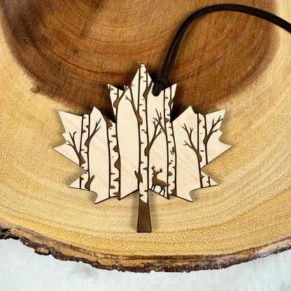 Maple wood Canadian maple leaf ornament with engraved deer and birch forest. Handmade and finished with a brown faux suede rope.