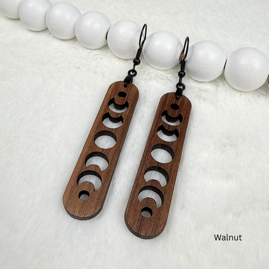 Walnut wood earrings with laser cut crescent moon. Dangle earrings with black stainless steel hooks and silicone backers. Finished with natural wood oil.