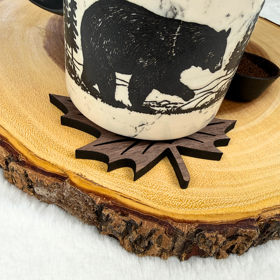 Maple leaf shaped wood coaster with coffee mug showing the Canadian inspired design