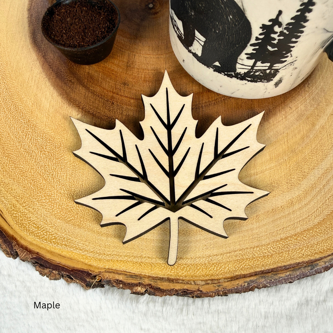 Maple wood maple leaf coaster with cut-out vein design under a coffee mug