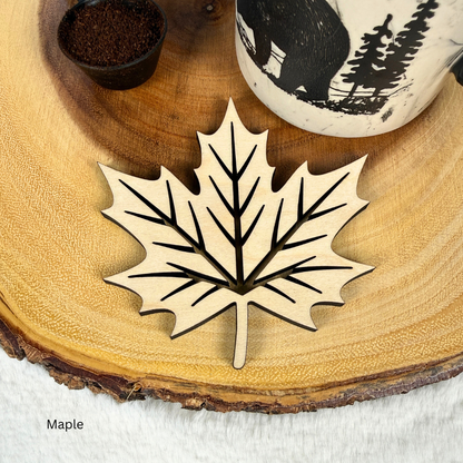 Maple wood maple leaf coaster with cut-out vein design under a coffee mug
