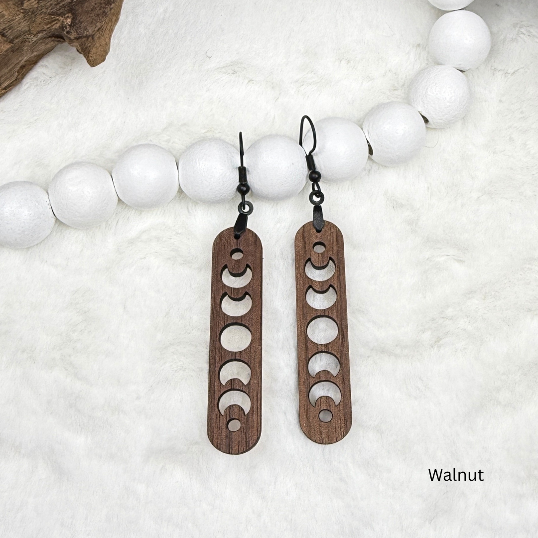 Walnut wood earrings with laser cut crescent moon. Dangle earrings with black stainless steel hooks and silicone backers. Finished with natural wood oil.