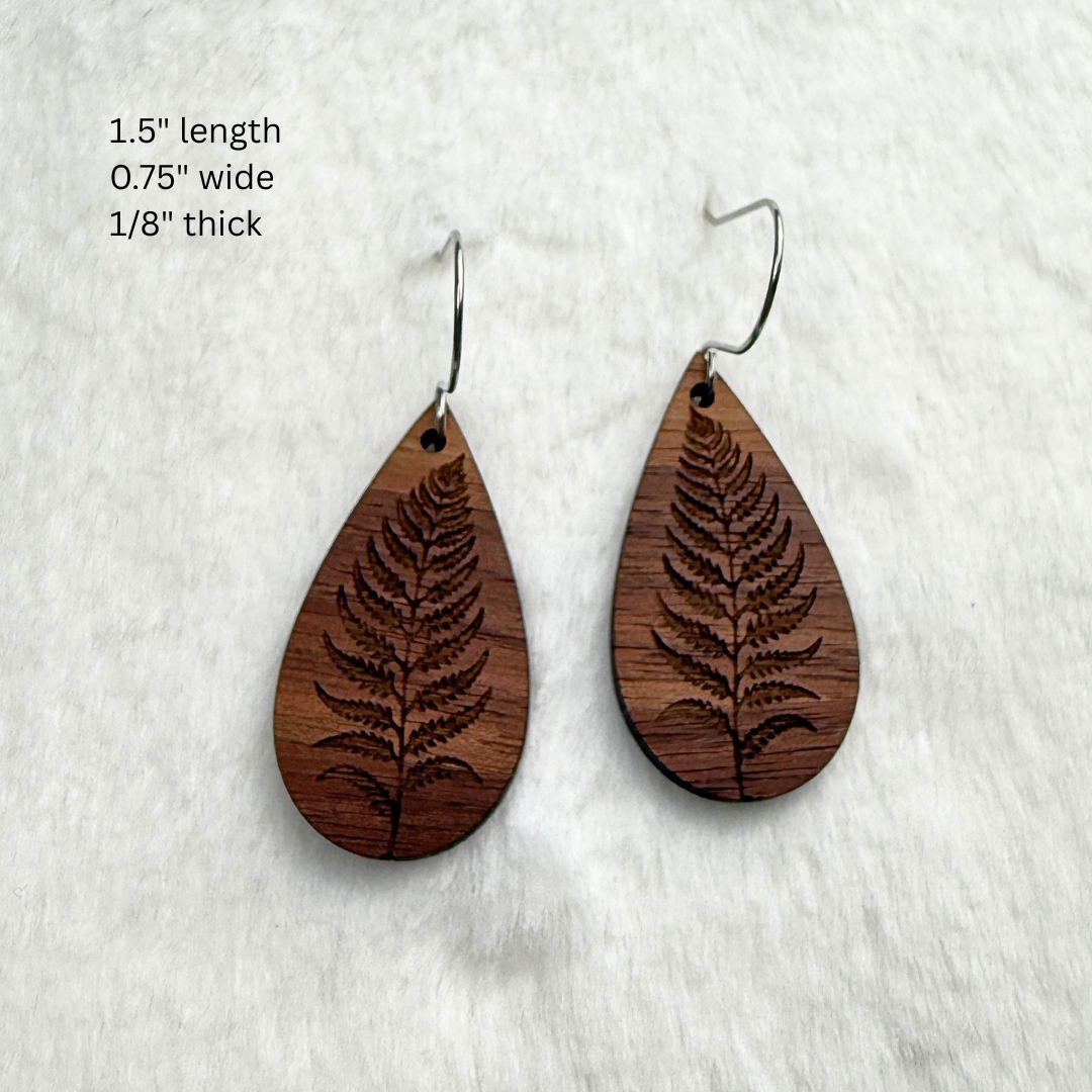 Fern leaf wooden earrings with stainless steel hooks. Finished with vegan wood oil. Laser engraved from walnut wood. Measurements are 1.5 inches long by 0.75 inches wide.