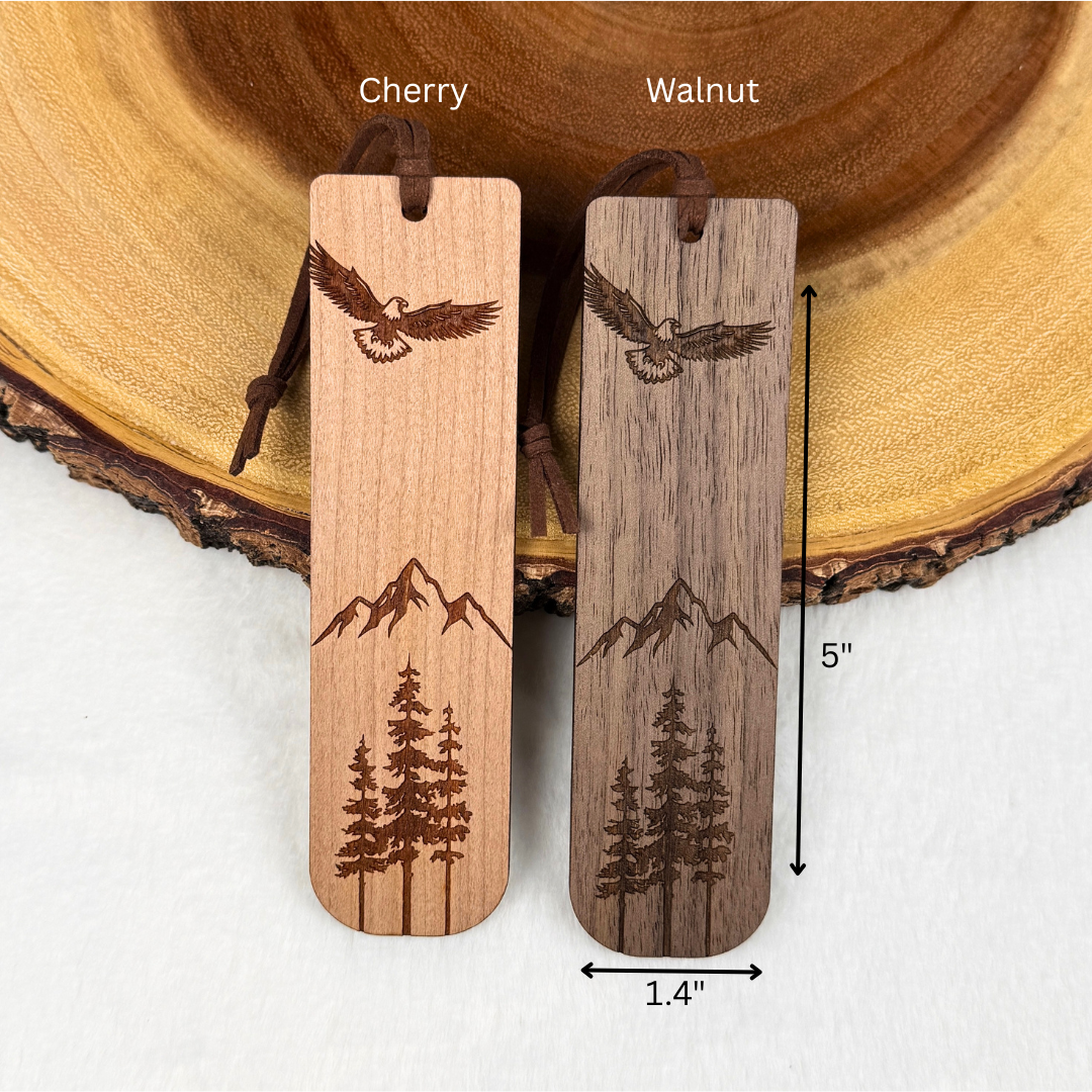 Engraved wooden bookmarks with an eagle, mountains, and pine trees, showing the measurements. Includes a brown faux suede rope. 