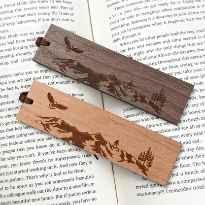 Cherry and walnut mountain and eagle wooden bookmarks displayed on an open book.