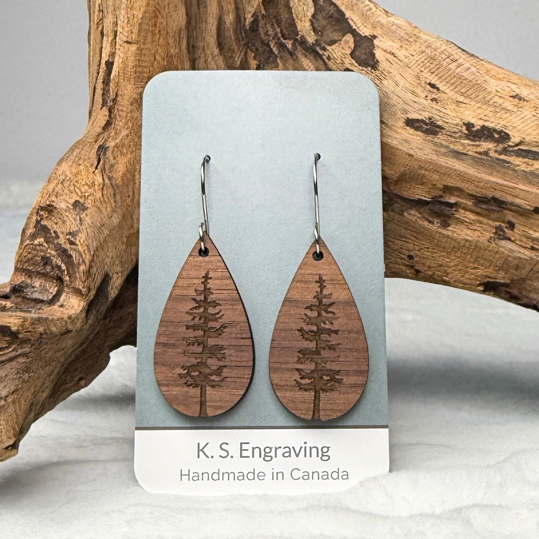 Teardrop shape wooden earrings with an engraved tree design made from walnut wood. Finished with vegan wood oil and stainless steel hooks. Hanging on K.S. Engraving display card.