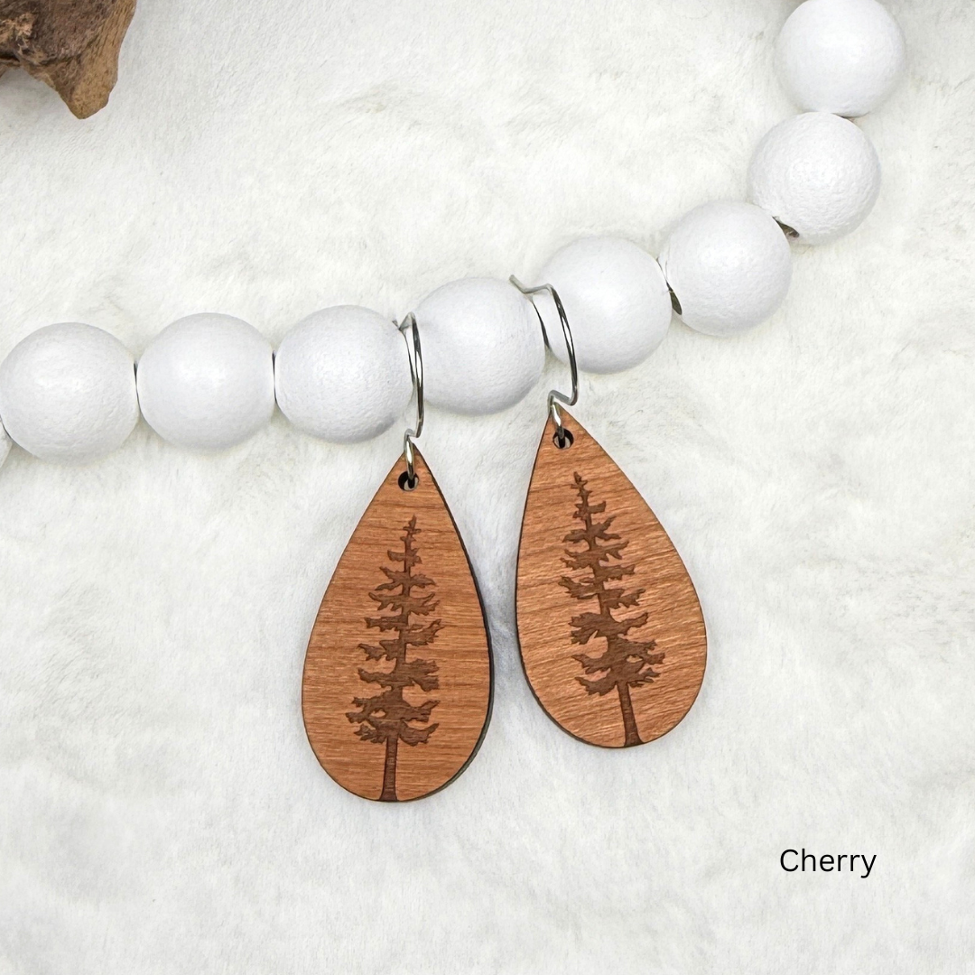 Teardrop shape wooden earrings with an engraved tree design made from cherry wood. Finished with vegan wood oil and stainless steel hooks. Hanging on white beads.