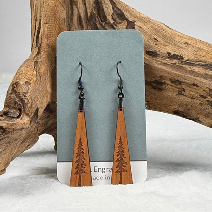 Wooden earrings with an engraved tree design made from cherry wood and finished with vegan wood oil on a card. Triangle shape with black stainless steel hooks.